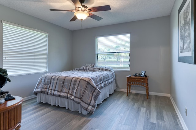 bedroom featuring ceiling fan, wood-type flooring, and a textured ceiling