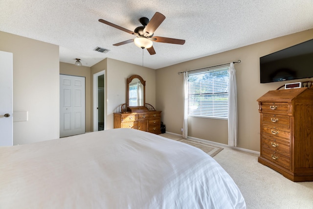 bedroom with light carpet, ceiling fan, and a textured ceiling