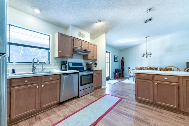 kitchen featuring appliances with stainless steel finishes, plenty of natural light, sink, and decorative light fixtures