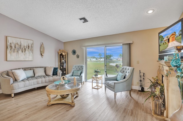 living room featuring a textured ceiling, light wood finished floors, baseboards, visible vents, and recessed lighting