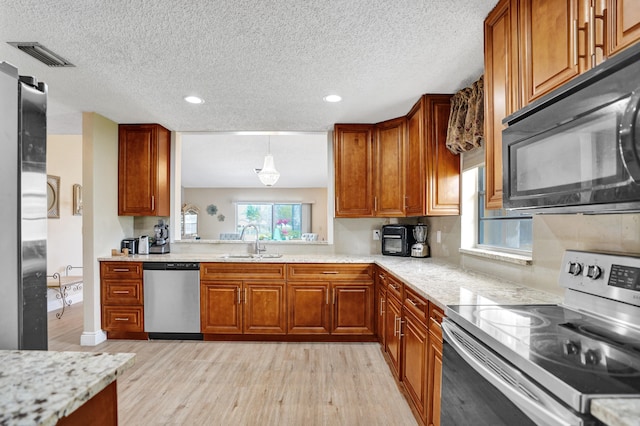 kitchen featuring visible vents, appliances with stainless steel finishes, brown cabinets, and a sink