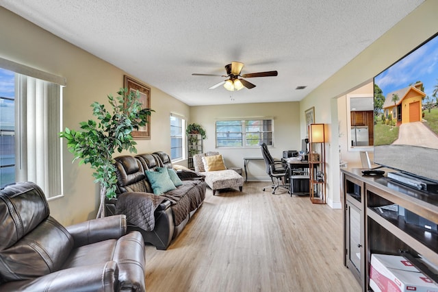 living room with a ceiling fan, a textured ceiling, visible vents, and light wood-type flooring