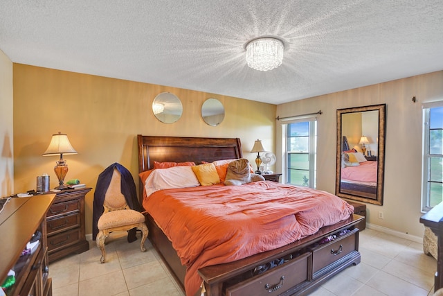 bedroom with light tile patterned floors, a textured ceiling, an inviting chandelier, and baseboards