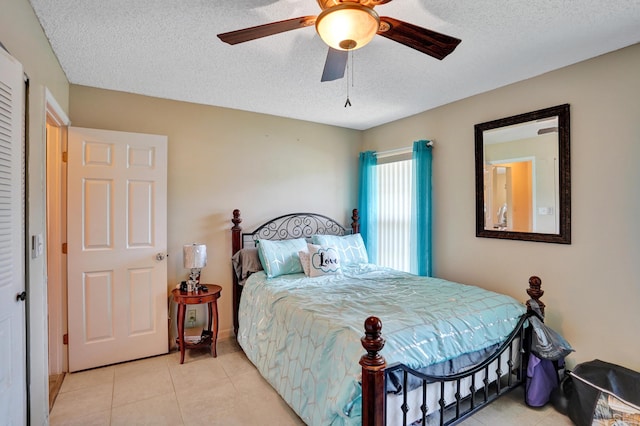 bedroom featuring ceiling fan, light tile patterned flooring, and a textured ceiling