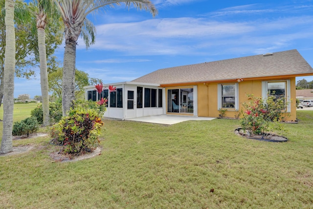 rear view of property with a sunroom, a patio area, a lawn, and stucco siding