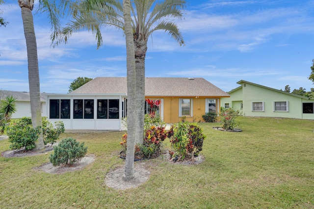 single story home featuring a shingled roof, a front yard, a sunroom, and stucco siding