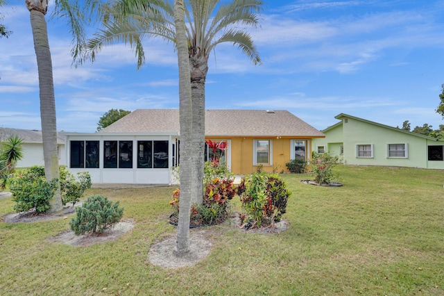 ranch-style home featuring stucco siding, a front lawn, a sunroom, and roof with shingles
