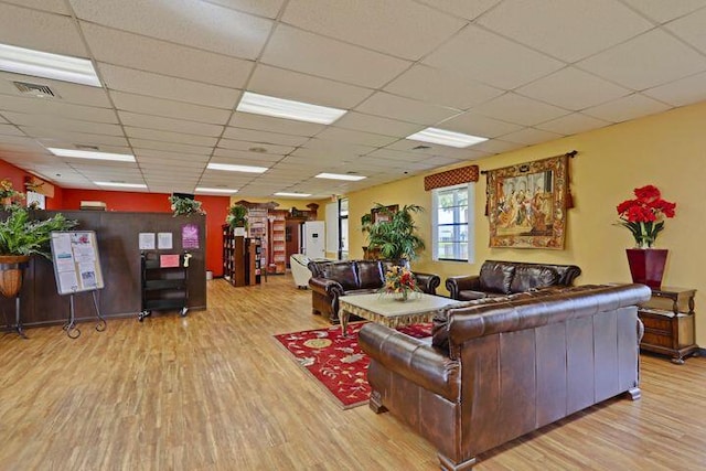 living area featuring a paneled ceiling, visible vents, and wood finished floors