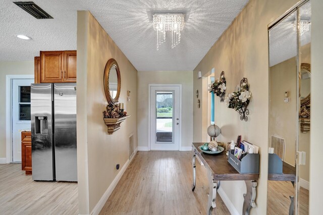 3570 Amalfi Dr, West Palm Beach, FL 33417 - foyer entrance featuring a textured ceiling, light wood finished floors, and a chandelier