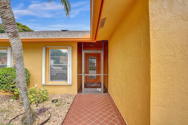 property entrance featuring a shingled roof and stucco siding