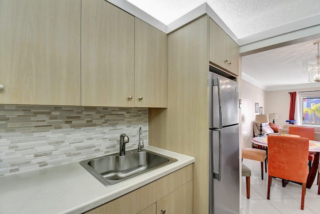 kitchen with sink, crown molding, light tile patterned floors, stainless steel fridge, and backsplash