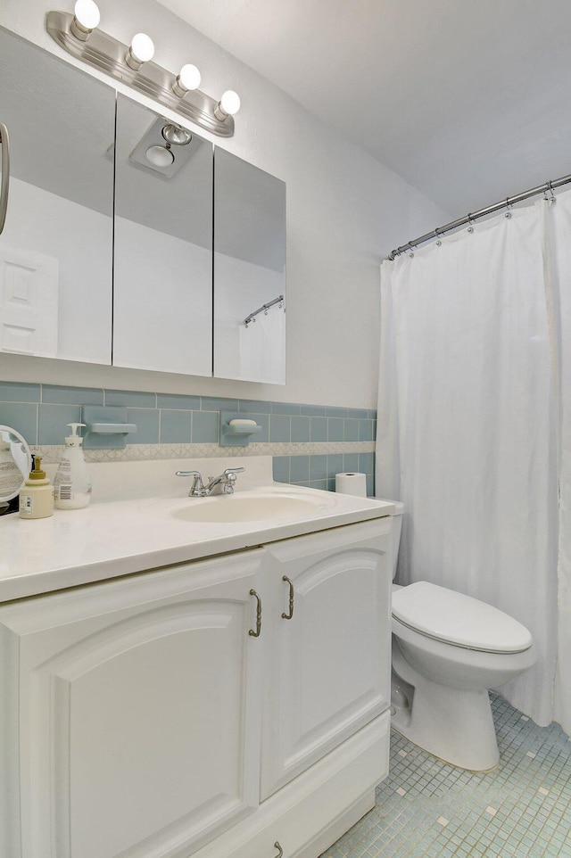 bathroom with tile patterned flooring, vanity, toilet, and tile walls