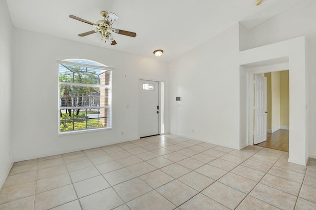 tiled empty room featuring vaulted ceiling and ceiling fan