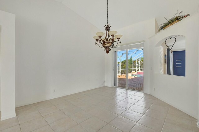 tiled empty room featuring high vaulted ceiling and a chandelier