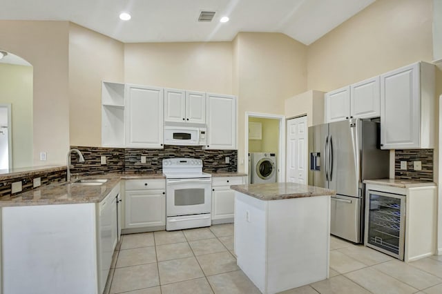 kitchen with sink, white appliances, a kitchen island, washer / dryer, and beverage cooler