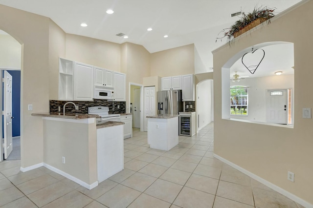 kitchen featuring white appliances, kitchen peninsula, and white cabinets