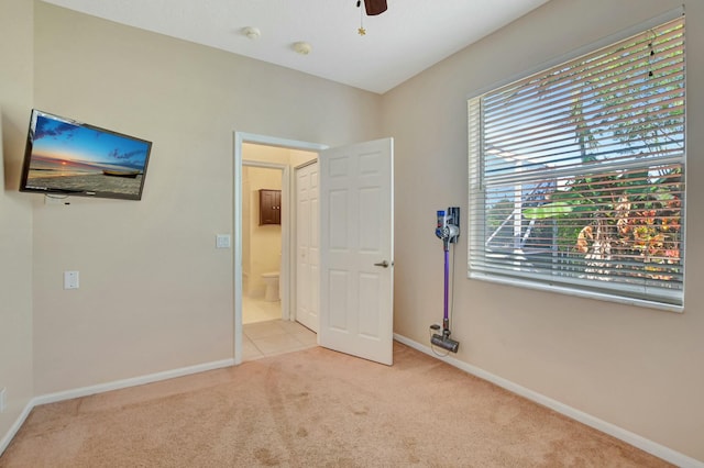 unfurnished bedroom with ceiling fan, connected bathroom, and light carpet