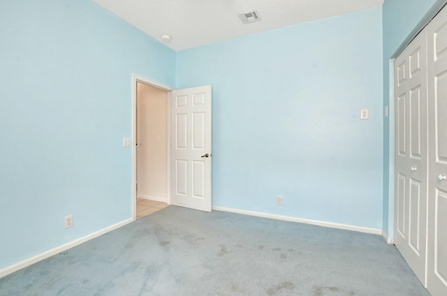 unfurnished bedroom featuring light colored carpet and a closet