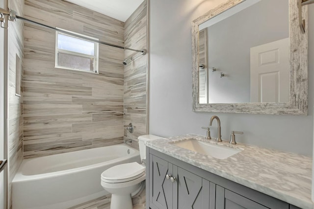 full bathroom featuring tiled shower / bath, vanity, and toilet