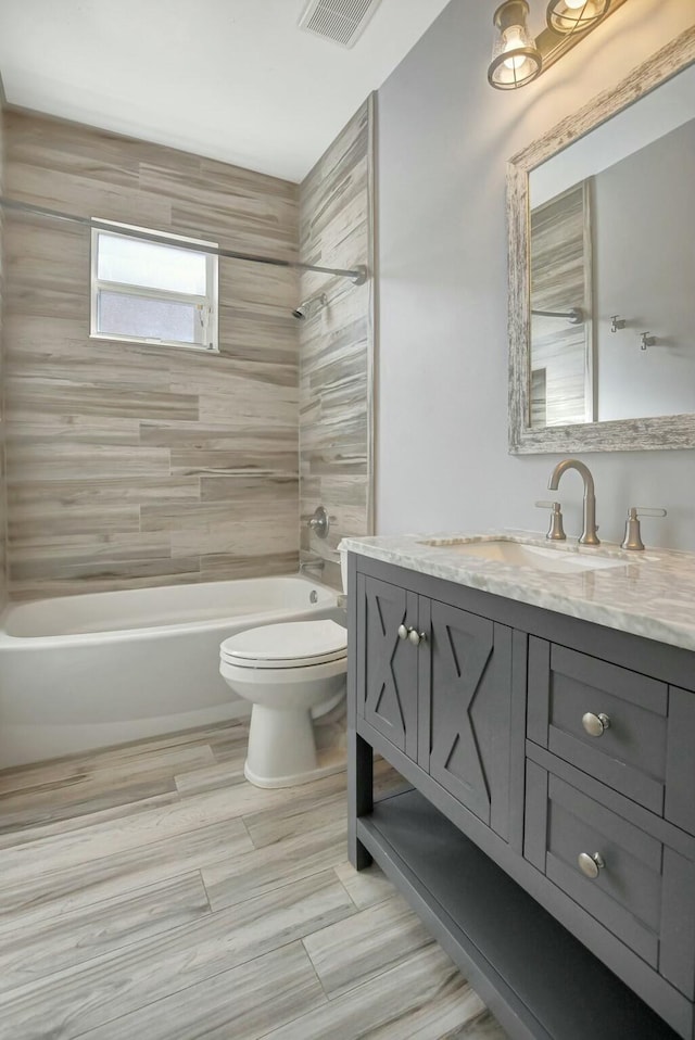 full bathroom featuring vanity, tiled shower / bath combo, and toilet