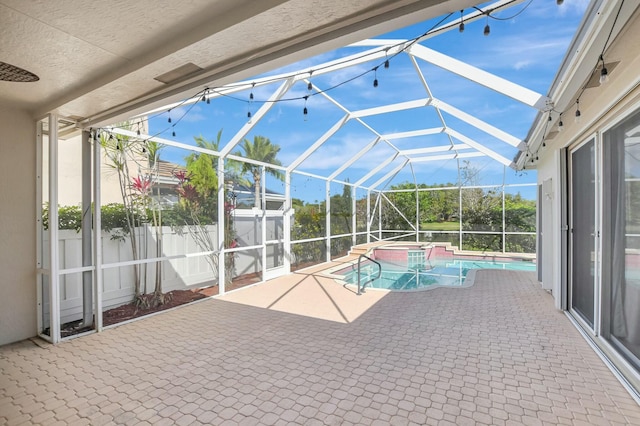 view of pool with an in ground hot tub, a patio area, and glass enclosure