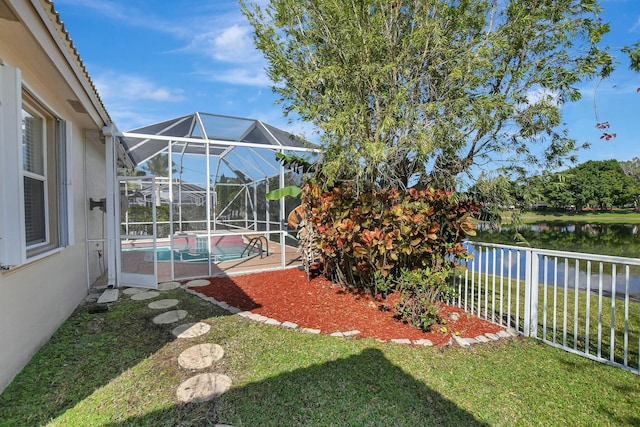 view of yard with a lanai, a patio, and a water view