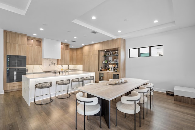 dining room featuring dark wood-type flooring, sink, and a tray ceiling