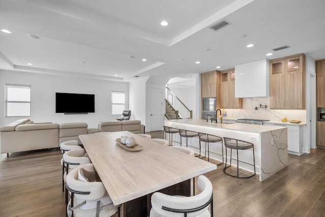 dining room featuring a raised ceiling, dark hardwood / wood-style floors, and sink