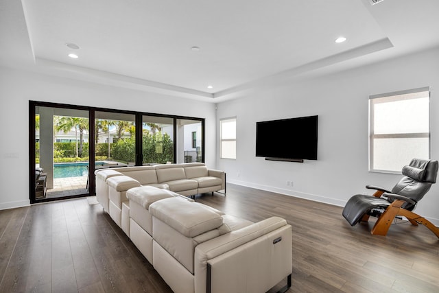 living room featuring a tray ceiling, dark hardwood / wood-style flooring, and a wealth of natural light