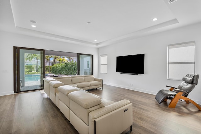 living room featuring a tray ceiling and wood-type flooring