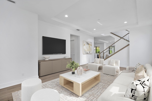 living room with light hardwood / wood-style flooring and a raised ceiling