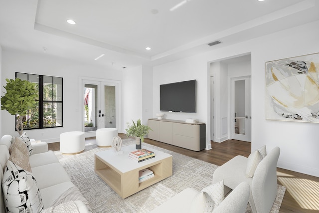 living room featuring french doors, a raised ceiling, and hardwood / wood-style flooring