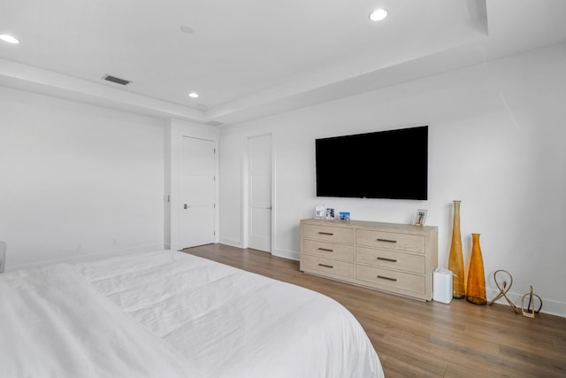 bedroom featuring hardwood / wood-style flooring and a tray ceiling