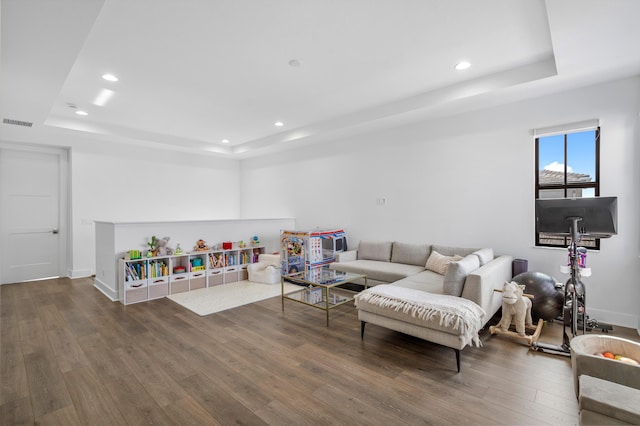 living room with dark wood-type flooring and a raised ceiling