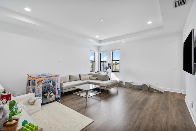 living room featuring dark wood-type flooring and a tray ceiling