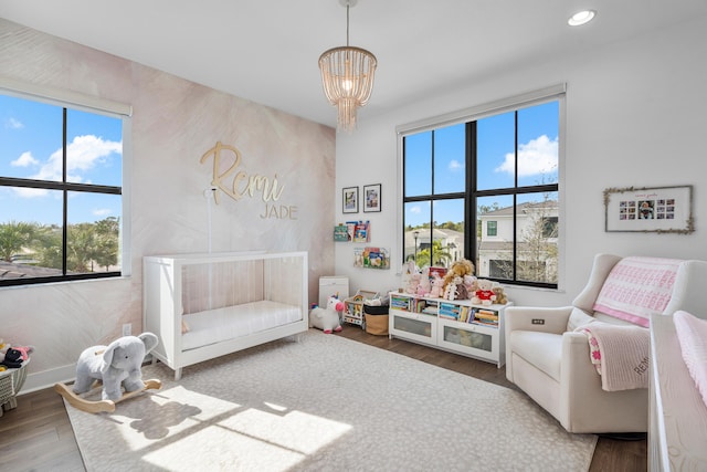 game room with hardwood / wood-style flooring, a wealth of natural light, and a chandelier