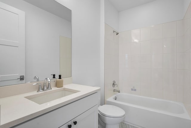 full bathroom featuring tiled shower / bath, vanity, and toilet