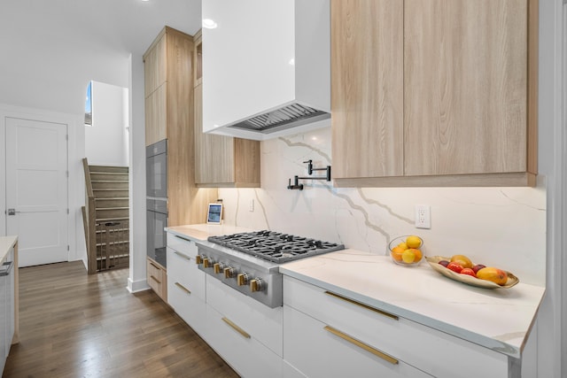 kitchen with white cabinets, decorative backsplash, custom exhaust hood, stainless steel gas stovetop, and light brown cabinets