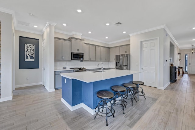 kitchen with sink, a center island with sink, light hardwood / wood-style flooring, a kitchen breakfast bar, and stainless steel appliances