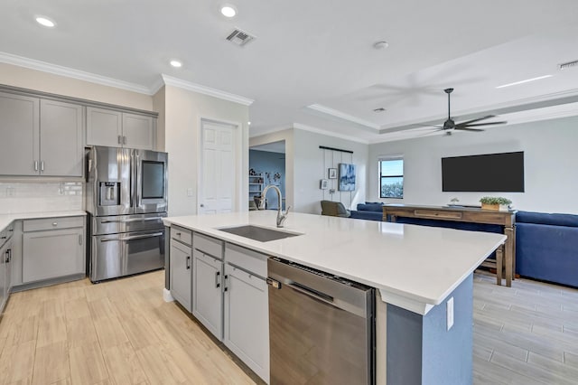 kitchen with sink, gray cabinets, stainless steel appliances, and an island with sink