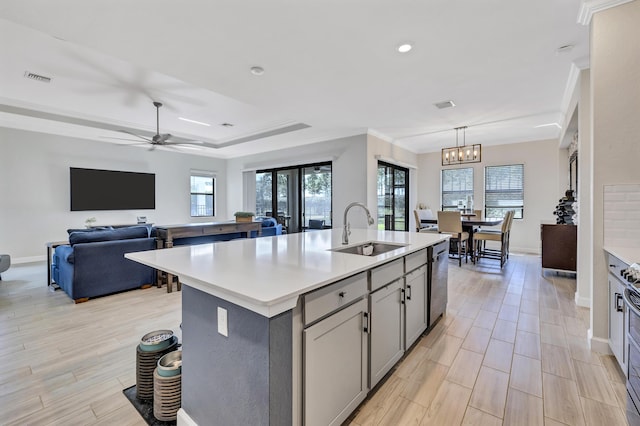 kitchen with sink, decorative light fixtures, light wood-type flooring, gray cabinets, and a kitchen island with sink