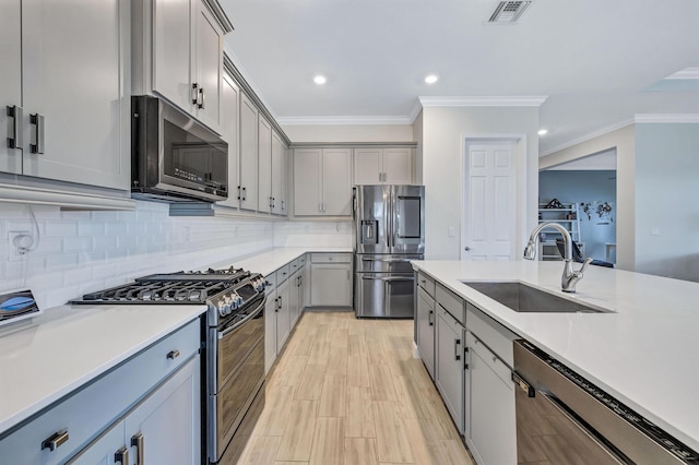 kitchen featuring sink, tasteful backsplash, ornamental molding, gray cabinets, and stainless steel appliances