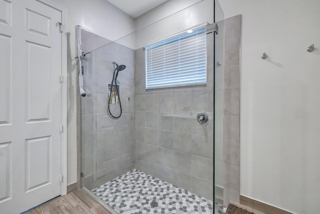 bathroom with hardwood / wood-style flooring and tiled shower