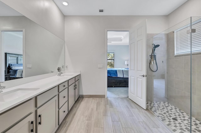 bathroom with hardwood / wood-style flooring, tiled shower, and vanity