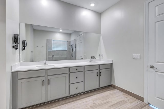 bathroom with vanity, hardwood / wood-style flooring, and tiled shower