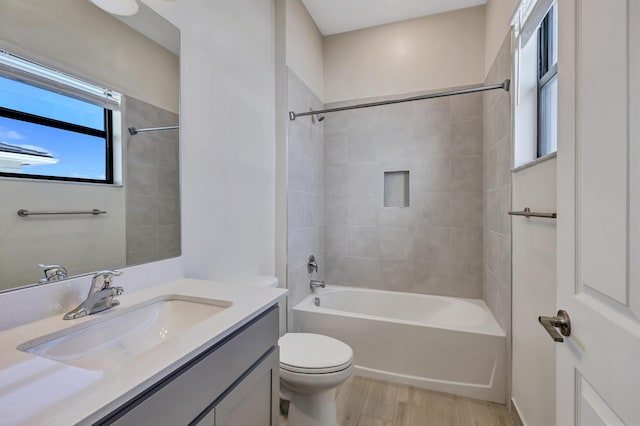 full bathroom with vanity, hardwood / wood-style floors, tiled shower / bath combo, and toilet