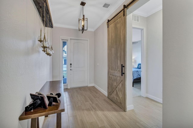 entrance foyer featuring crown molding, a barn door, and light wood-type flooring