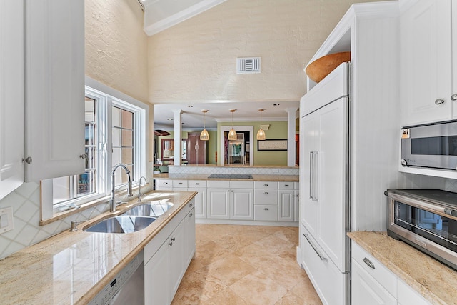 kitchen with appliances with stainless steel finishes, white cabinetry, sink, decorative backsplash, and hanging light fixtures