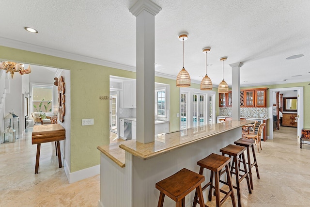 kitchen featuring a breakfast bar, decorative light fixtures, decorative backsplash, stainless steel dishwasher, and light stone counters