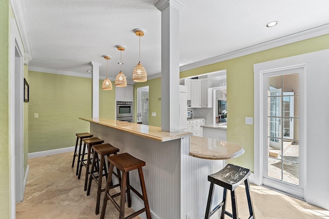 kitchen featuring pendant lighting, a breakfast bar, white cabinetry, ornamental molding, and kitchen peninsula